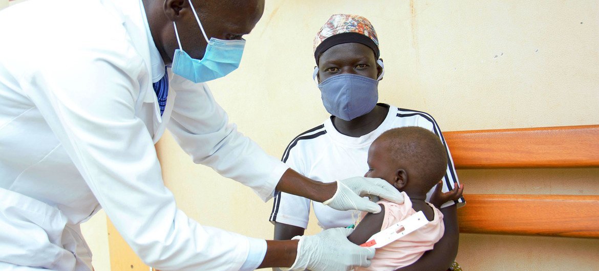 Bebê de um ano, no Uganda, sendo atendido por pessoal hospitalar