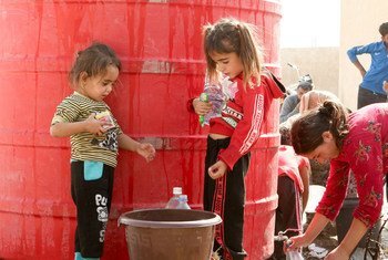 Deux enfants attendent de collecter de l'eau apportée par l'UNICEF à Tall Tamr, dans le nord-est de la Syrie.