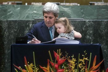 Former United States Secretary of State John Kerry, accompanied by his grand-daughter, signs the Paris Agreement at UN headquarters in April 2016.