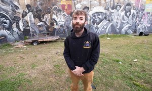 Henry Lipkis in front of his monumental mural depicting a traditional parade in New Orleans.