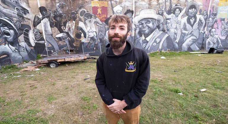 Henry Lipkis in front of his monumental mural depicting a traditional parade in New Orleans.