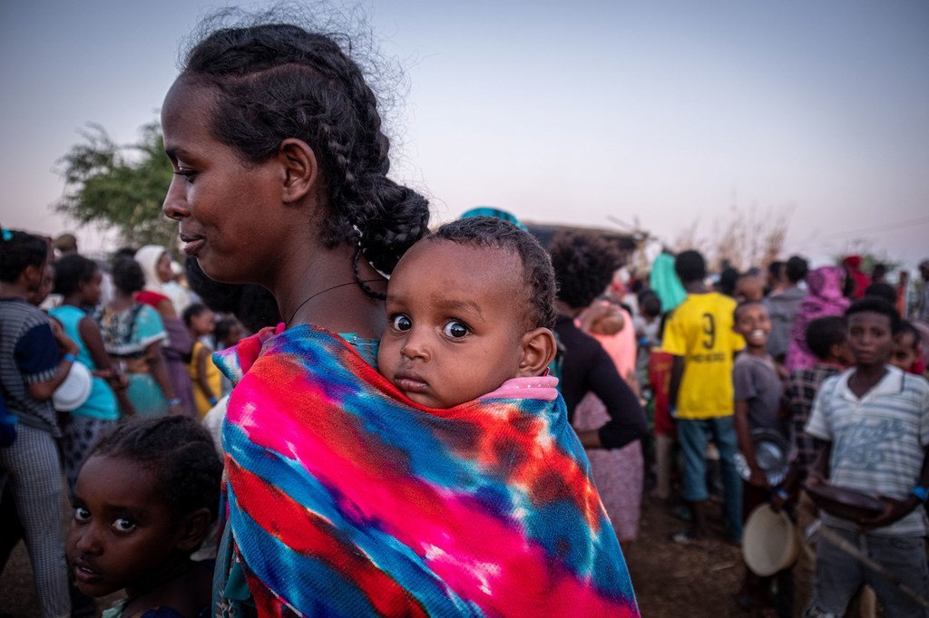 Une réfugiée du Tigré fait la queue avec son bébé pour recevoir de la nourriture dans le camp de réfugiés d'Um Rakuba au Soudan.