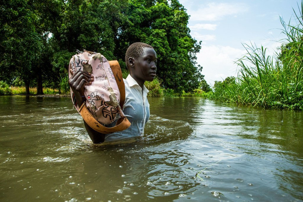 在南苏丹朱巴郊区，尼罗河泛滥，一名女孩从学校步行回家。