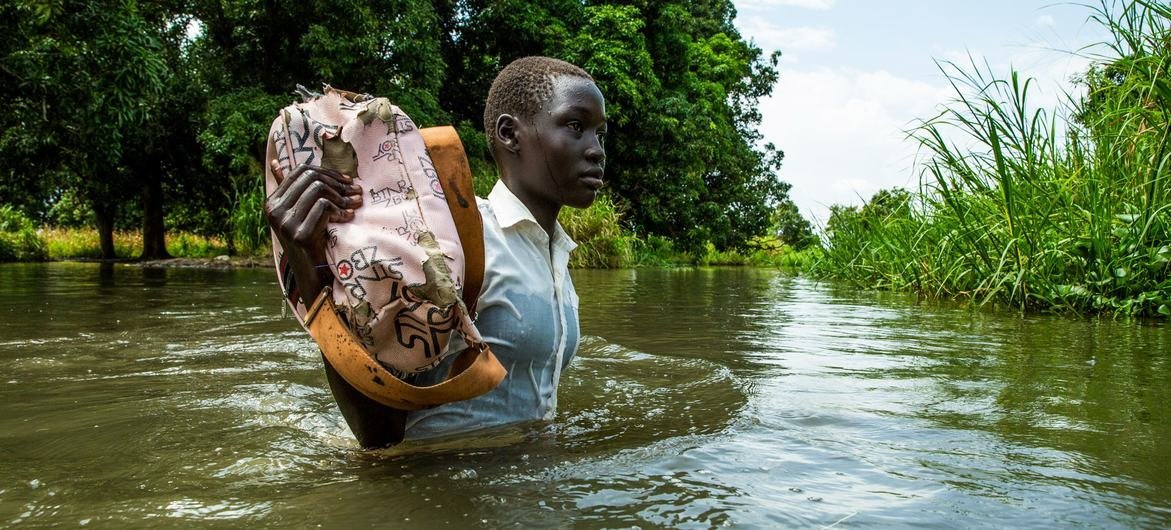 Una niña sostiene sus libros para que no se mojen de camino a casa desde la escuela en la aldea de Walangwalang, que se salvó de las inundaciones del río, en las afueras de Juba, en Sudán del Sur.