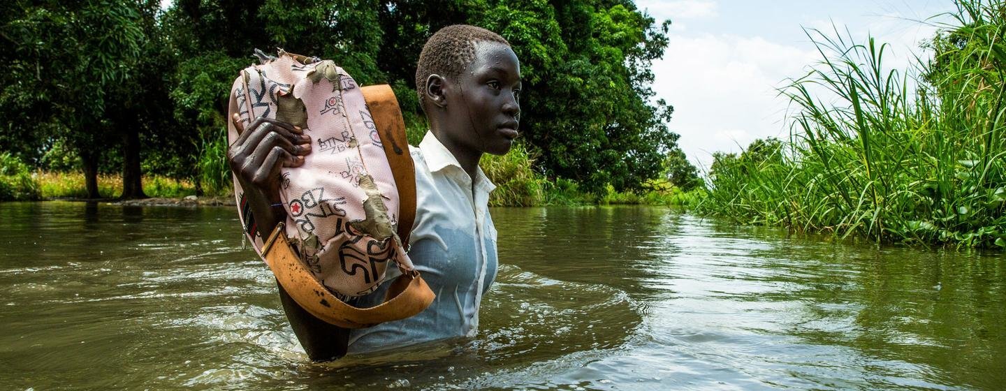 Una niña sostiene sus libros para que no se mojen de camino a casa desde la escuela en la aldea de Walangwalang, que se salvó de las inundaciones del río, en las afueras de Juba, en Sudán del Sur.