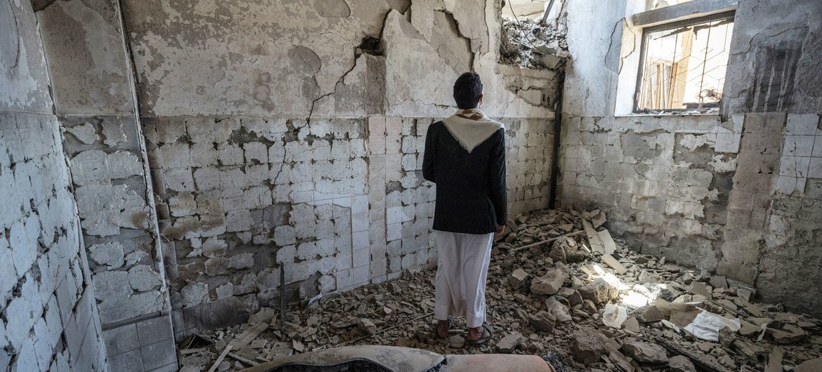 也门萨达，一位当地居民站在一处被炸毁的政府办公楼内，他的身后是一枚导弹的弹壳。