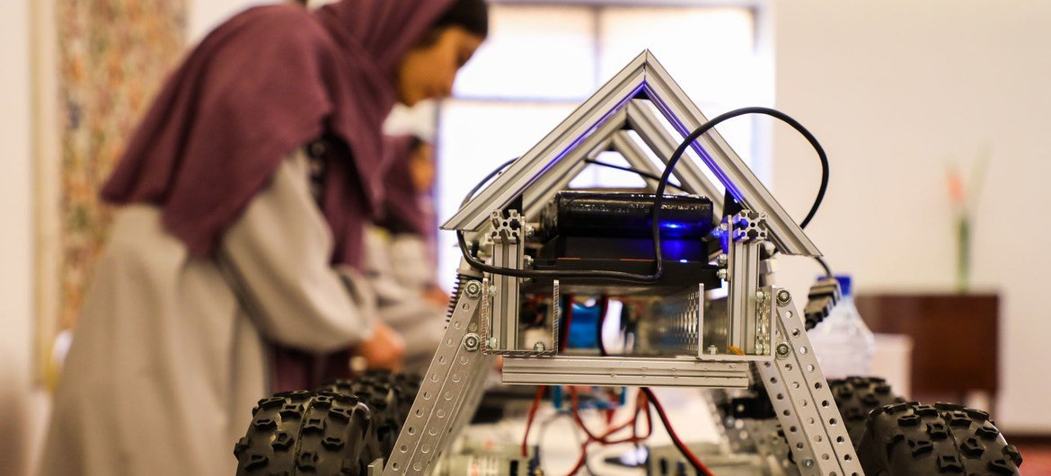 Una joven afgana muestra durante una exhibición en Kabul cómo funciona un robot que ella construyó.