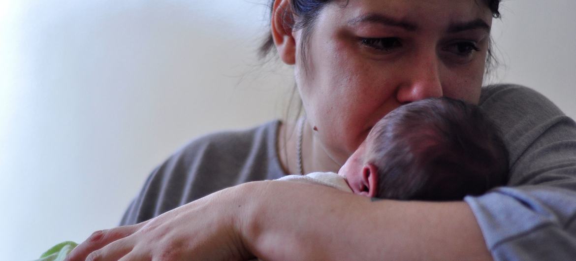 Uma mãe segura seu bebê recém-nascido em um hospital em Kiev, na Ucrânia.