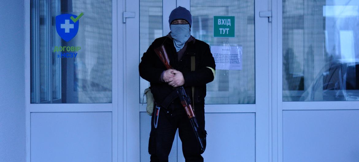 Homem armado em frente à hospital na Ucrânia. 