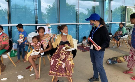 An IOM staff member speaks with people affected by the floods in Timor-Leste.