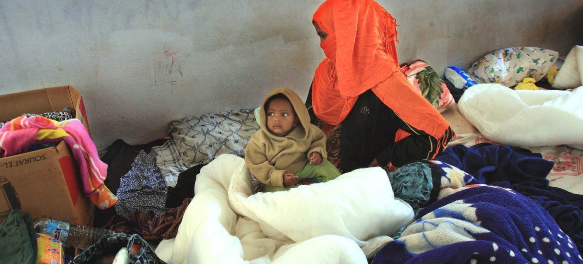 Une femme somalienne est assise avec son enfant d'un an, dans le centre de détention de Ganfoda, près de Benghazi, après avoir fui les violences dans son pays et pénétré illégalement en Libye.