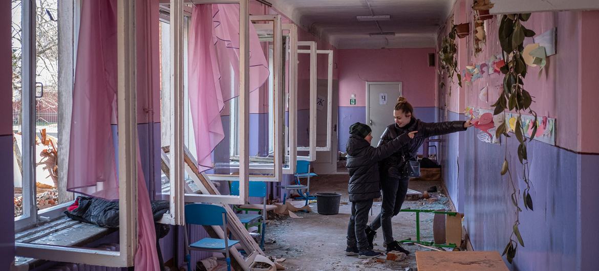 Unos niños miran los trabajos de arte en un aula sembrada de cristales rotos y otros escombros en Chernihiv, Ucrania.