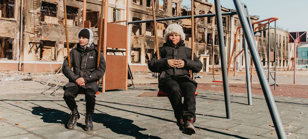 Deux enfants de 14 ans jouent sur les balançoires de leur ancienne école à Kharkiv, dans le nord-est de l'Ukraine, détruite par des bombardements.