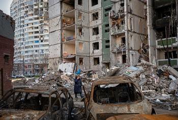Mulher passa por prédios de apartamentos e veículos destruídos em Chernihiv, na Ucrânia