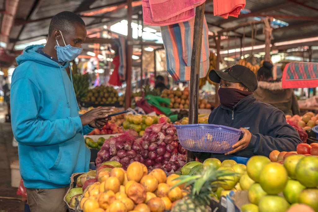 一名男子在肯尼亚的一个绿色市场上购买新鲜农产品。