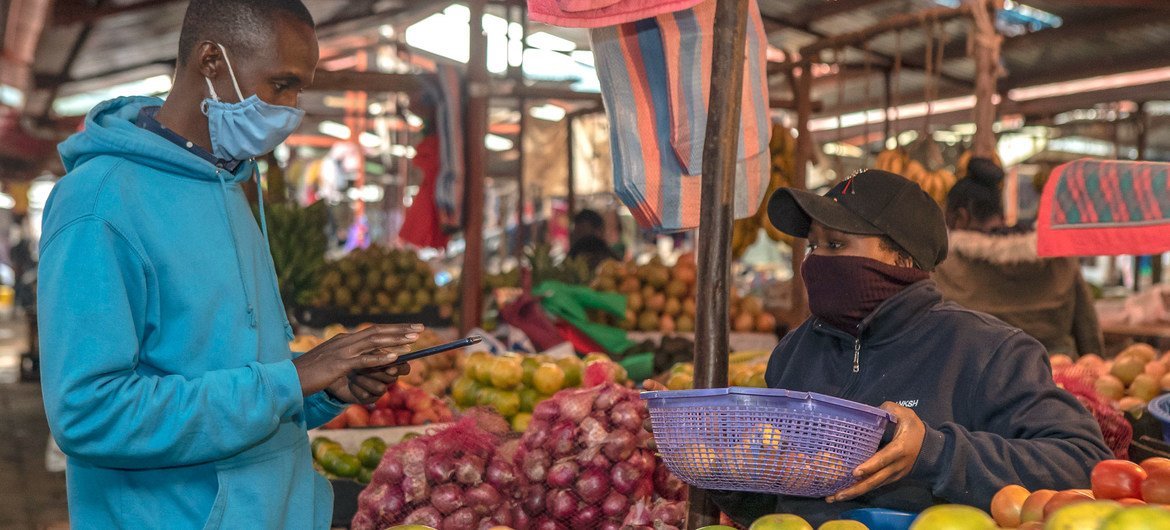 Un joven compra fruta en un mercado de Kenya.