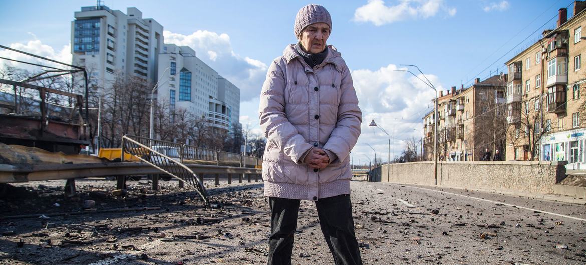 यूक्रेन की राजधानी कीयेव में बमबारी के बाद मलबे के पास खड़ी एक महिला.