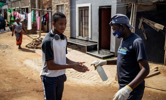 Em Joanesburgo, na África do Sul, homens desinfetam mãos como medida de combate à Covid-19