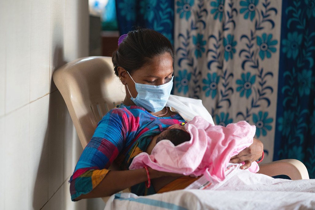 Una mujer amamanta a su bebé en una sala de parto en la India poco después de dar a luz.