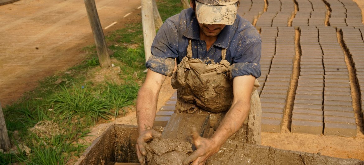 Un ladrillero artesanal en Uruguay pone el material crudo en el molde para ponerlo a secar.