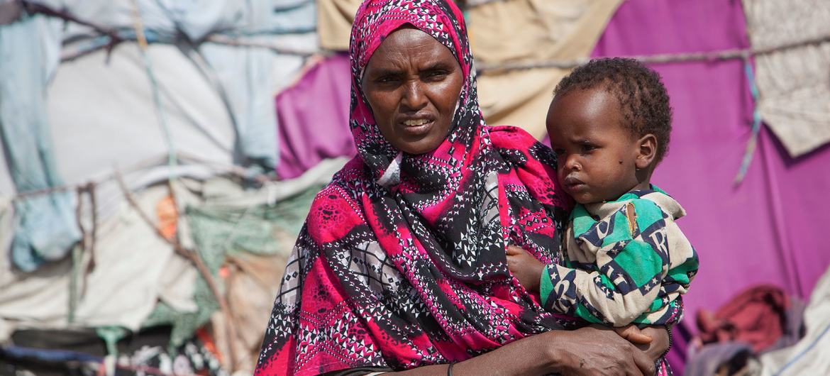 Mulher segura criança em campo de deslocados na Somália depois de ser forçada a deixar sua casa devido à seca