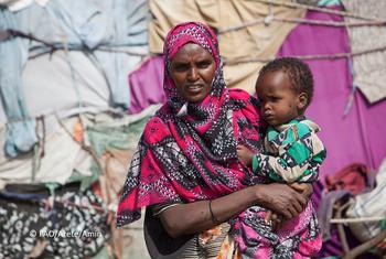 在索马里的一个流离失所者营地，一位母亲抱着她的孩子，因为干旱他们被迫离家。