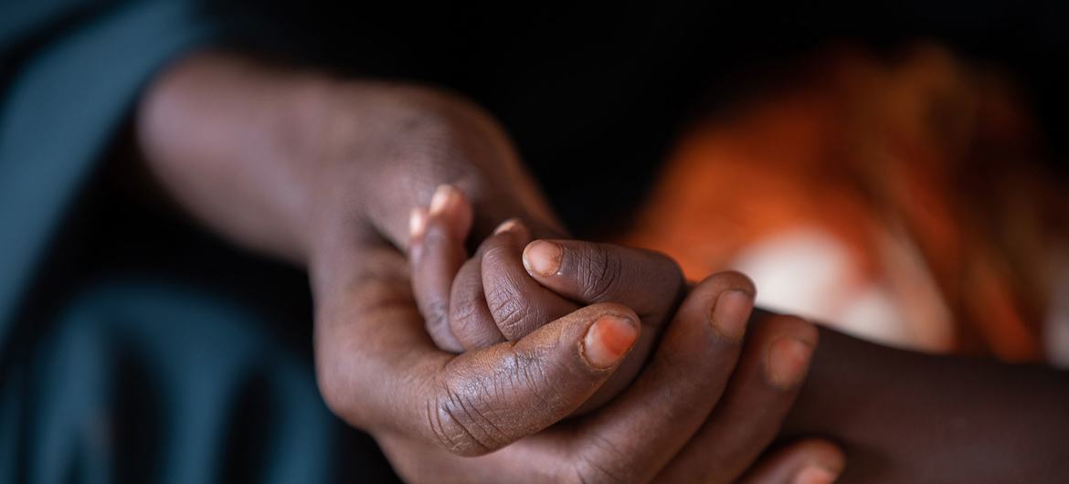 Una mujer sostiene la mano de su hijo de dos años en un centro de salud financiado por el PMA en Dolow, Somalia.