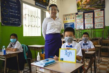 Una maestra y sus alumnos practican medidas de seguridad COVID en una escuela de Camboya.