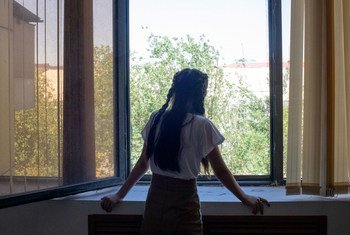 فتاة تبلغ من العمر 14 عاما تنظر من النافذة في كازاخستان. تمكنت من معالجة مشاعر التوتر والقلق بمساعدة طبيب نفساني تربوي.
