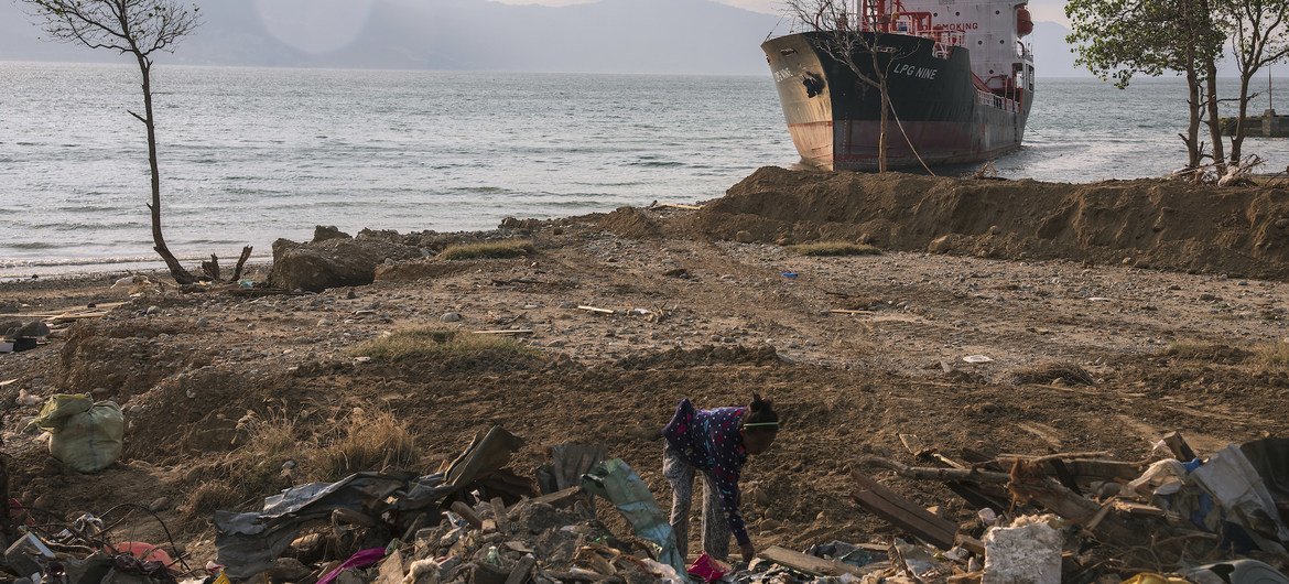 A woman in Indonesia searches through the rubble at a beach in Palu, Indonesia, that was entirely washed away by a tsunami a few days earlier. In the background is a beached ship, which was carried ashore by the waves. (October 2018)