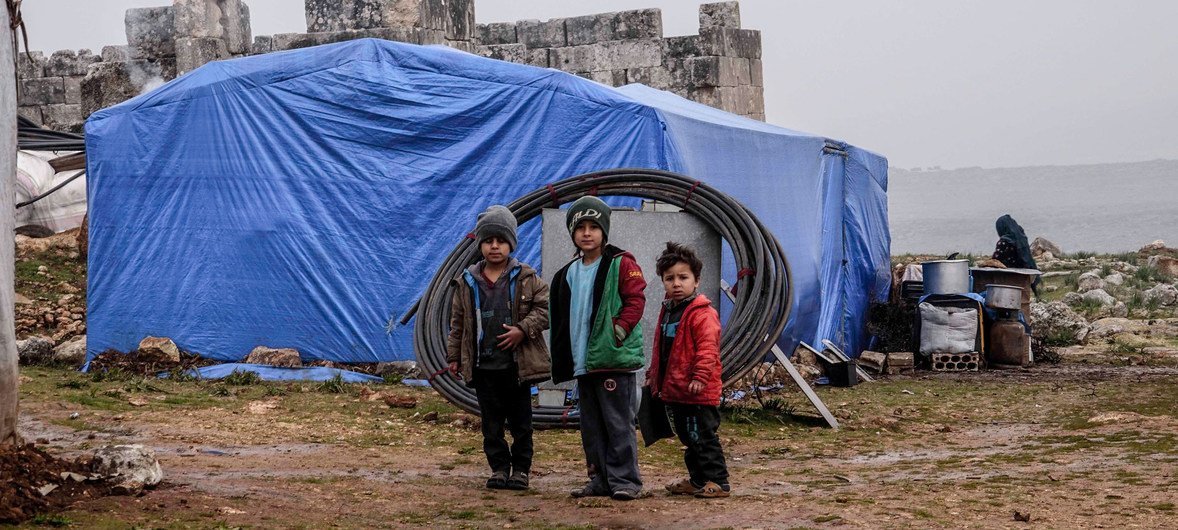 Children pose outside a tent in a camp for displaced people in Idlib, northern Syria. 