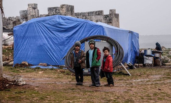 Children pose outside a tent in a camp for displaced people in Idlib, northern Syria. 
