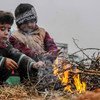 أطفال يلهون أمام مخيم للنازحين في جنوب إدلب، بسوريا