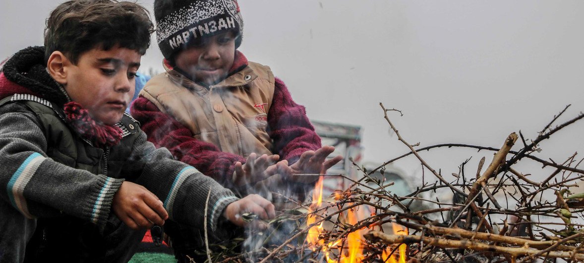 सीरिया के पश्चिमोत्तर इलाक़े इदलिब के दक्षिणी हिस्से में विस्थापित लोगों लिए बनाए एक एक शिविर में सर्दी का मुक़ाबला करने की कोशिश करते कुछ बच्चे.