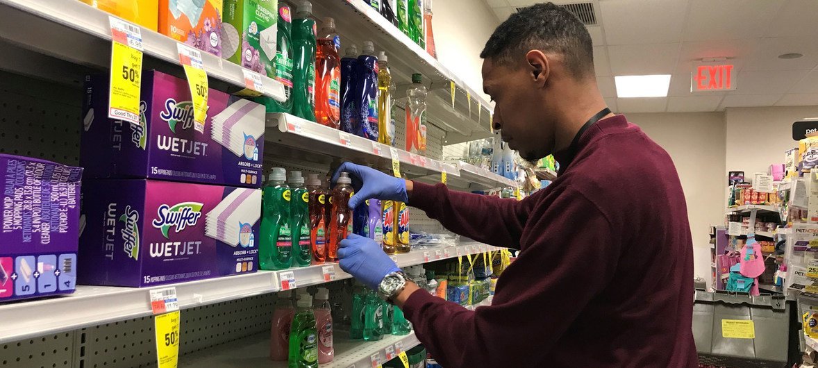 Un empleado de una farmacia de Nueva York lleva guantes para protegerse del coronavirus mientras repone los jabones en una estantería