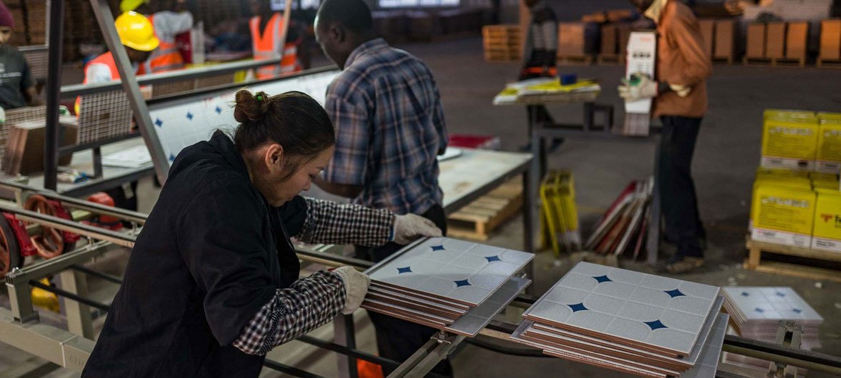 A woman measures products at a ceramic tile factory in Kenya.