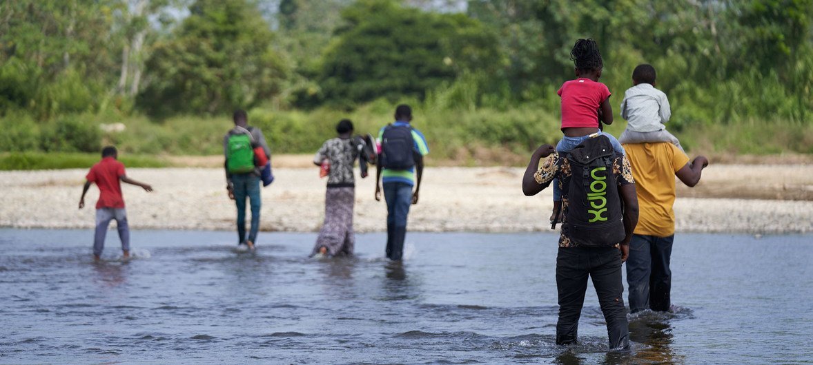 Los hermanos angoleños Romeu y Kulutwe y sus familias cruzan el río Tuquesa hacia el Bajo Chiquito, el primer pueblo panameño en la frontera con Colombia.