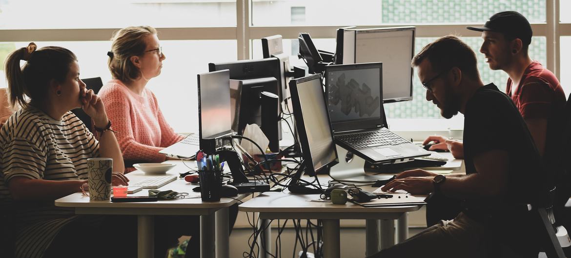 A group of people work on their computers in an office. 