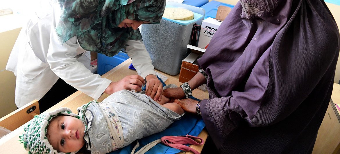 अफ़ग़ानिस्तान के कन्दाहार में एक क्लीनिक में एक माँ अपने बच्चे की चिकित्सा देखभाल कराते हुए.