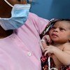ممرضة تقدم الرعاية الأولية لطفل حديث الولادة وهي ترتدي القناع الواقي في أحد المراكز الصحية في أبيدجان جنوب كوت ديفوار
