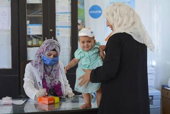 امرأة تحضر حفيدتها البالغة من العمر ثمانية أشهر لإجراء فحص طبي في عيادة صحية في ريف حماة الشمالي في سوريا.