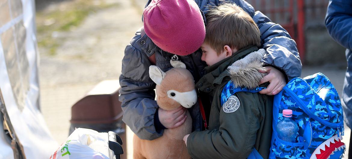 Une fillette ukrainienne réconforte son frère âgé de six ans alors qu'ils s'apprêtent à quitter un centre soutenu par l'UNICEF en Roumanie pour leur prochaine destination.