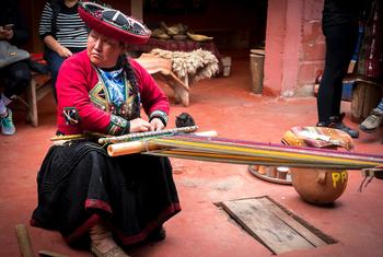 在秘鲁钦切罗区的街头，一名妇女在编织。
