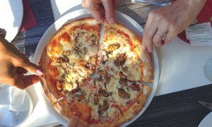 أصدقاء يزورون كرواتيا، ويتشاركون في تناول البيتزا وهو ما يشير إلى أهمية السلامة الغذائية للسياحة والازدهار الاقتصادي.