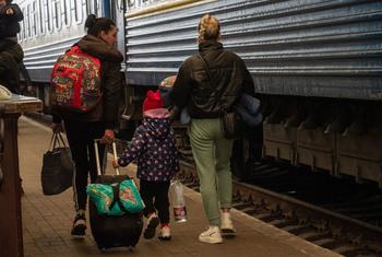 Des femmes et des enfants montent à bord de trains à la gare de Lviv en Ukraine.