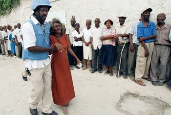 Un officier de police des Nations Unies aide une femme âgée à se rendre à l'isoloir dans la capitale haïtienne Port-au-Prince (archive)