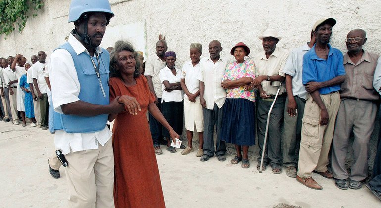 A UN police officer helps an elderly woman to a polling station in the capital of Haiti, Port-au-Prince. 