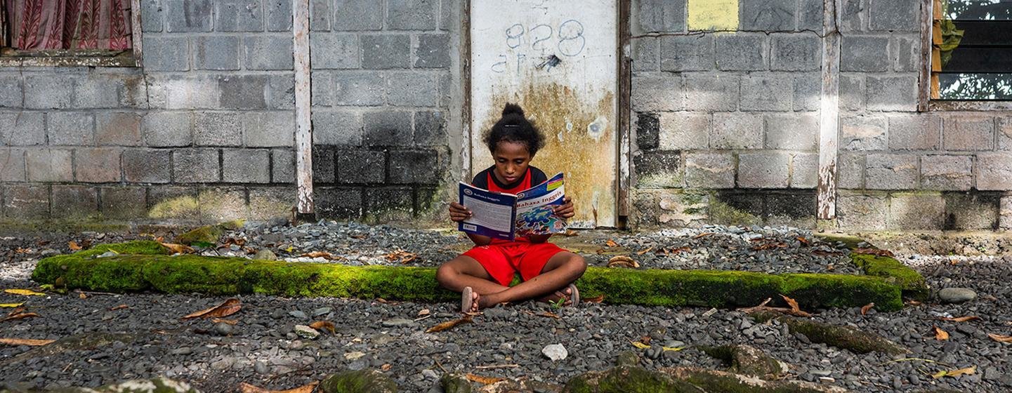 Une fille lit un livre devant sa maison en Papouasie, l'une des provinces les plus pauvres d'Indonésie.