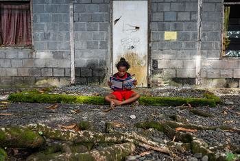 A girl reads a book in front of her house in Papua, one of Indonesia's poorest provinces.