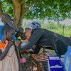 Uma profissional de saúde se prepara para imunizar uma jovem em uma escola primária no distrito de Busia, no Uganda.